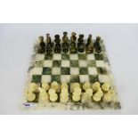 A carved stone chess set with 7.5 cm (h) king.