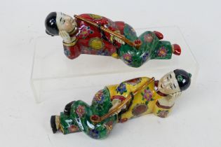 A pair of ceramic figures depicting reclining opium smokers, each approximately 19 cm (l).