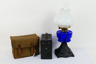 An oil lamp with cast iron base, blue glass font and milk glass shade,