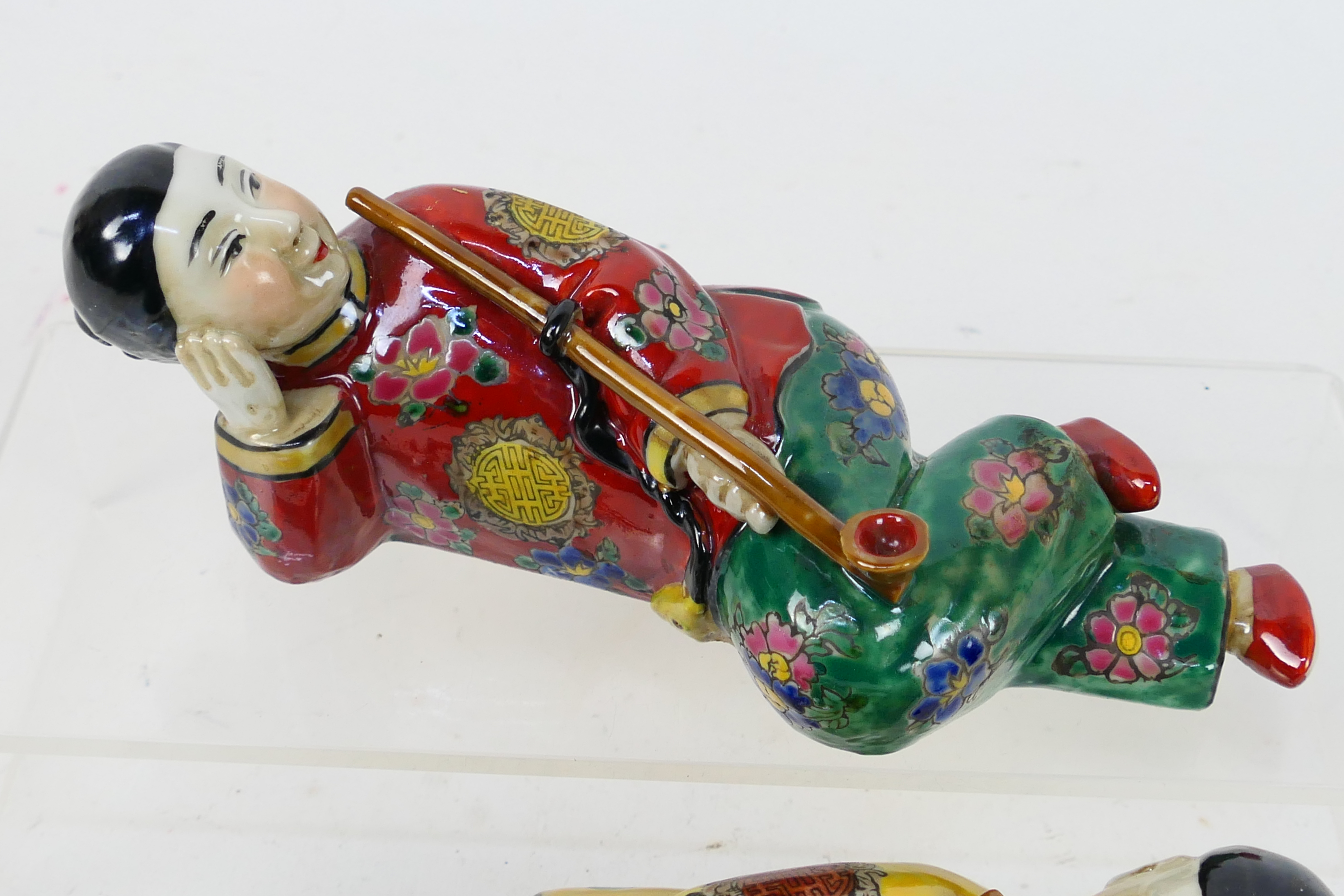 A pair of ceramic figures depicting reclining opium smokers, each approximately 19 cm (l). - Image 3 of 11