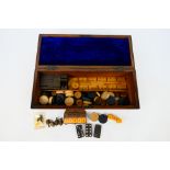 A burr wood veneered games compendium box containing cribbage board, dominoes,