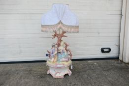 A large figural table lamp depicting a courting couple seated below a tree,
