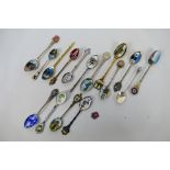A small group of silver and white metal souvenir spoons, predominantly enamelled,