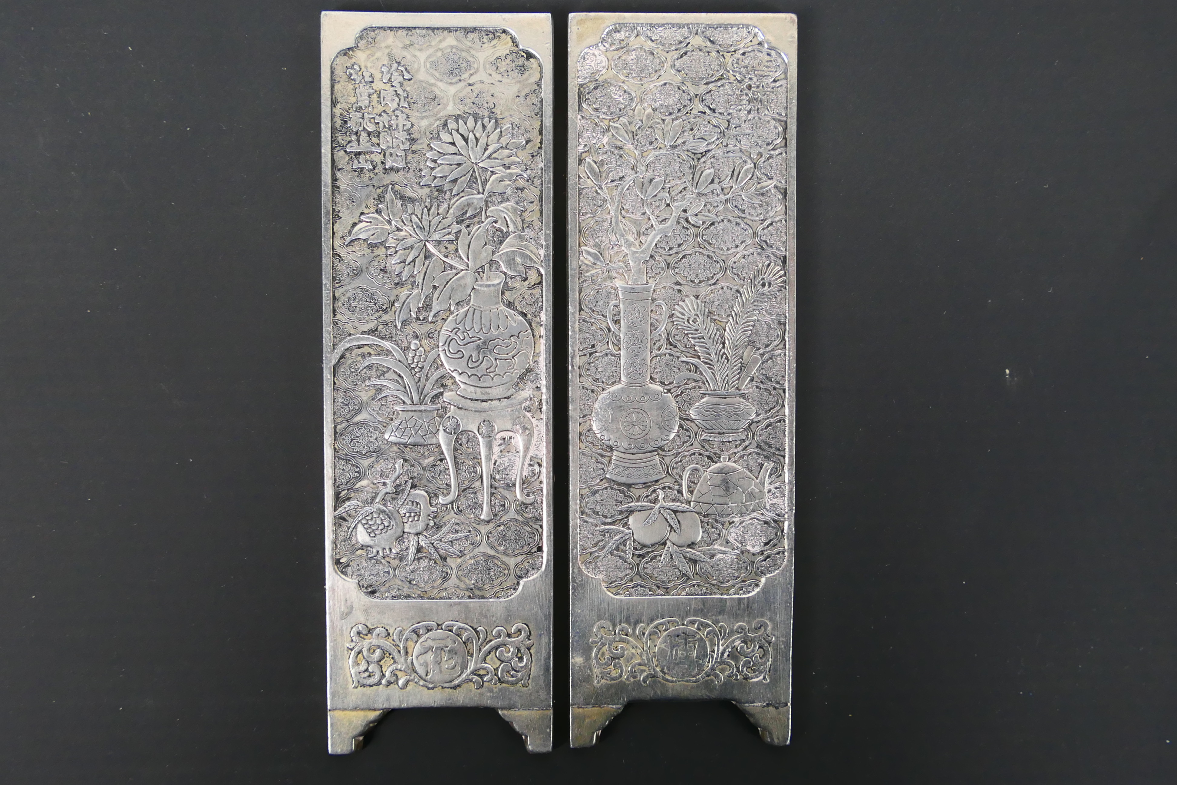 A pair of Chinese white metal plaques having bogu pattern decoration, 15 cm x 4.5 cm.