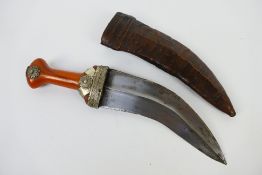 An Arab jambiya with 19 cm (l) blade having medial ridge, amber coloured white metal mounted grip,