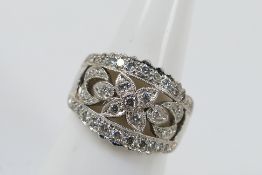 A platinum dress ring with a central diamond floral design with single outer rows of round