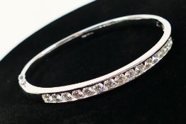 An 18ct white gold Diamond hinged bangle containing fifteen round brilliant cut Diamonds set in