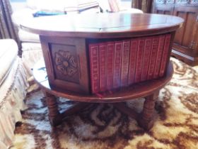 A circular oak coffee table incorporating bookshelves below with books included in the lot if