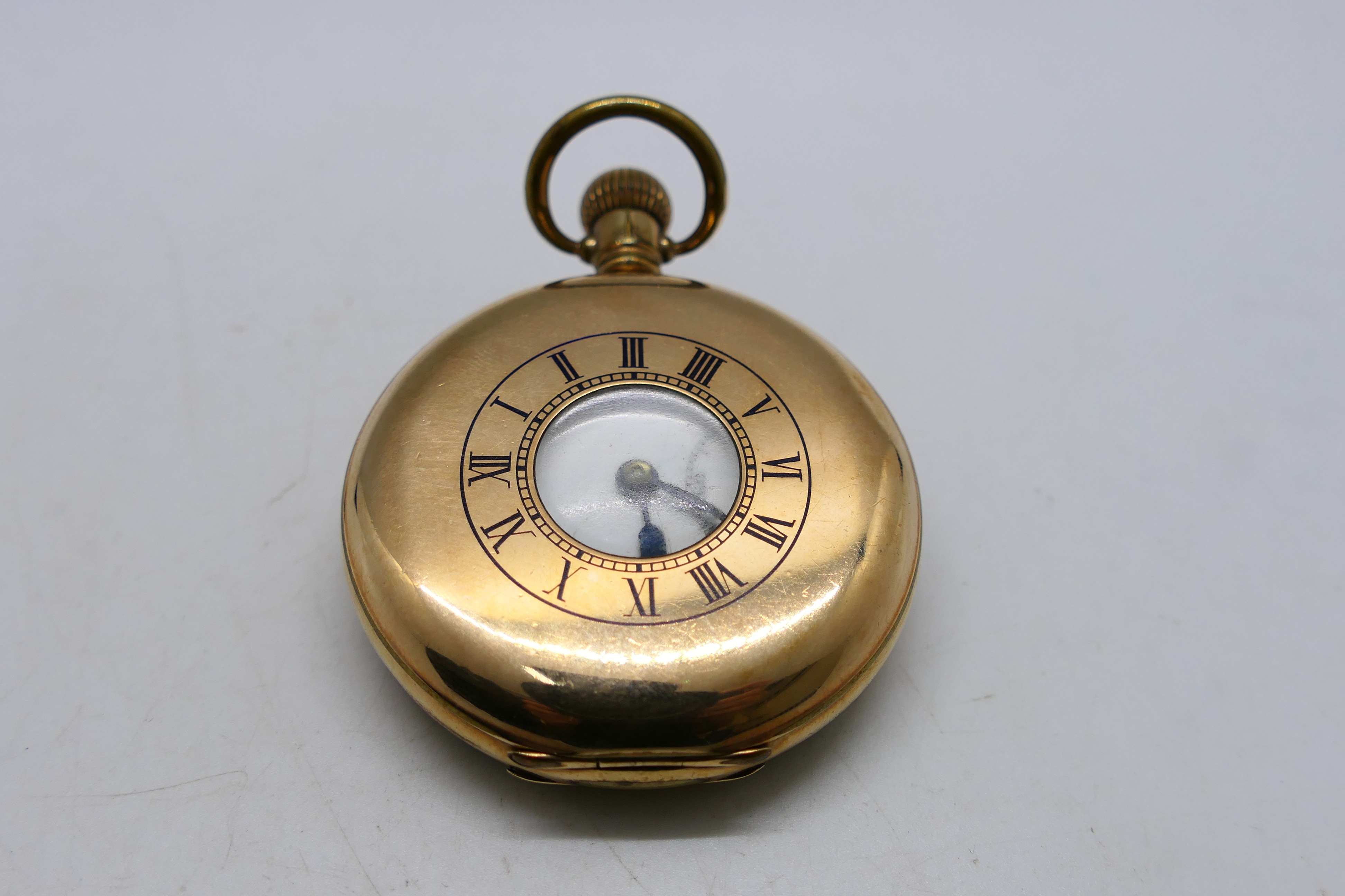 A gold plated half hunter pocket watch, Roman numerals to a white enamel dial,