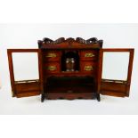 An early 20th century oak smokers cabinet with twin bevel glazed doors opening to reveal four