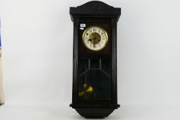 A dark brown wall clock. Wall clock is marked Glocken-Gong. Wall clock comes with key and pendulum.