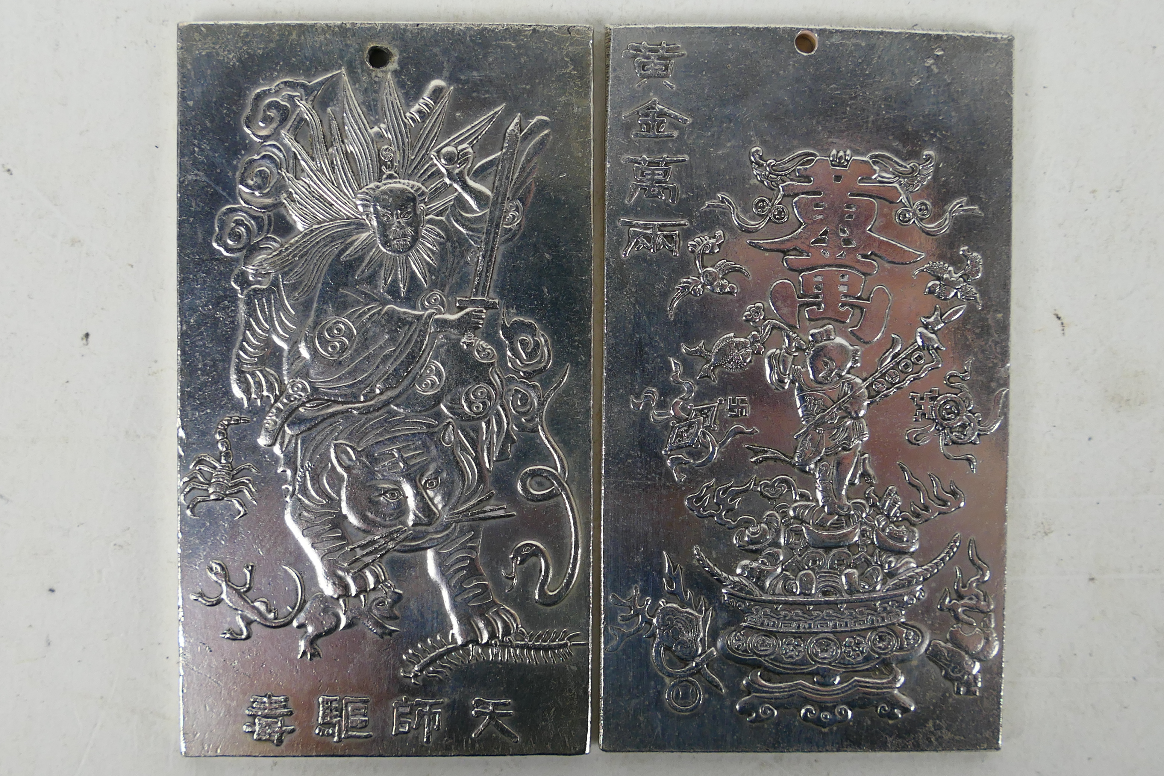 Two Chinese white metal plaques / trade tokens one decorated with a warrior riding a tiger,