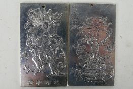 Two Chinese white metal plaques / trade tokens one decorated with a warrior riding a tiger,