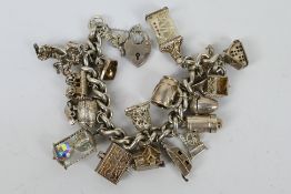 A silver charm bracelet with approximately 20 silver and white metal charms, 110 grams / 3.5 ozt.