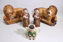 A pair of Staffordshire style fireside lions, two monk form jugs and a novelty teapot,