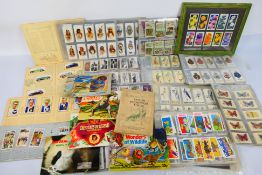 A collection of cigarette and tea cards, contained in albums and sleeves and one framed display.
