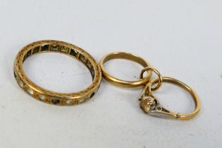 A 9ct gold charm in the form of an engagement and wedding ring and a yellow metal eternity ring