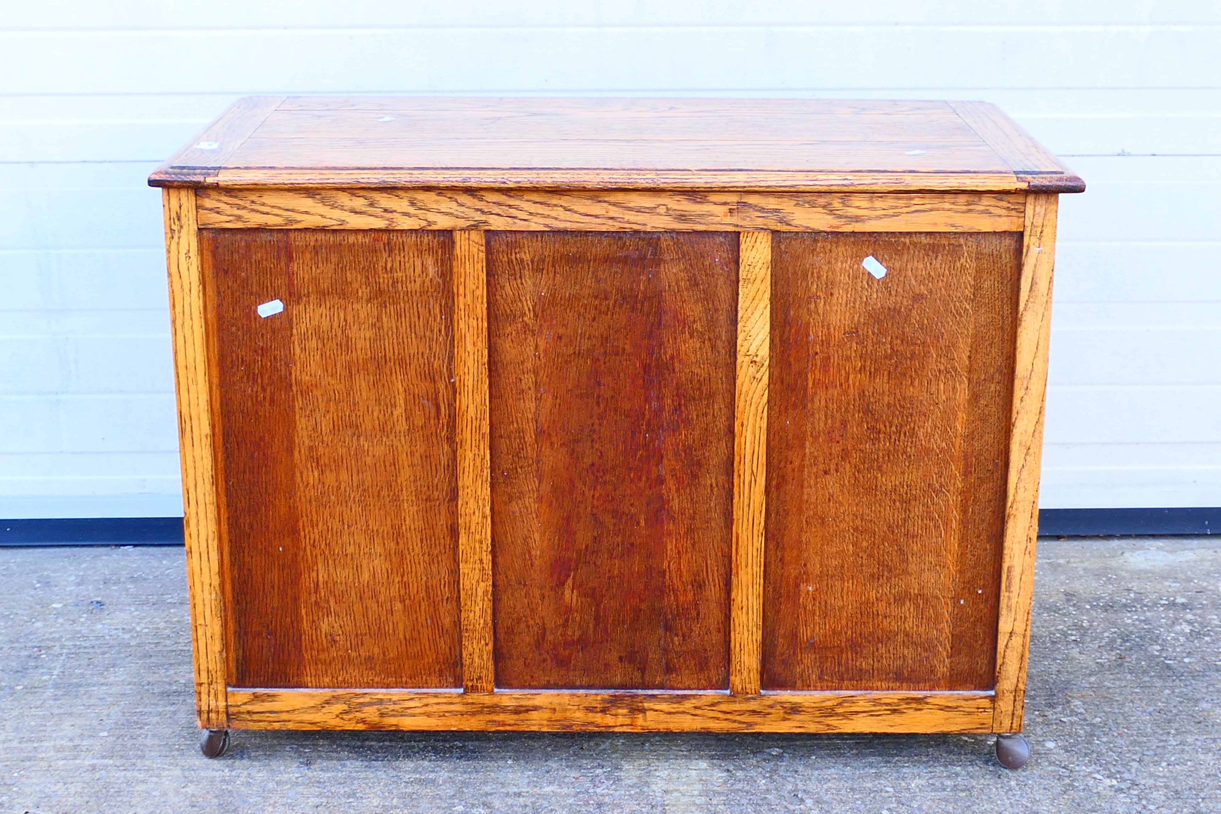 An oak blanket chest with three panel front and hinged top, approximately 68 cm x 95 cm x 47 cm.