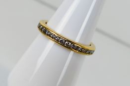 A high purity yellow metal, channel set diamond full eternity ring, stamped 18k,
