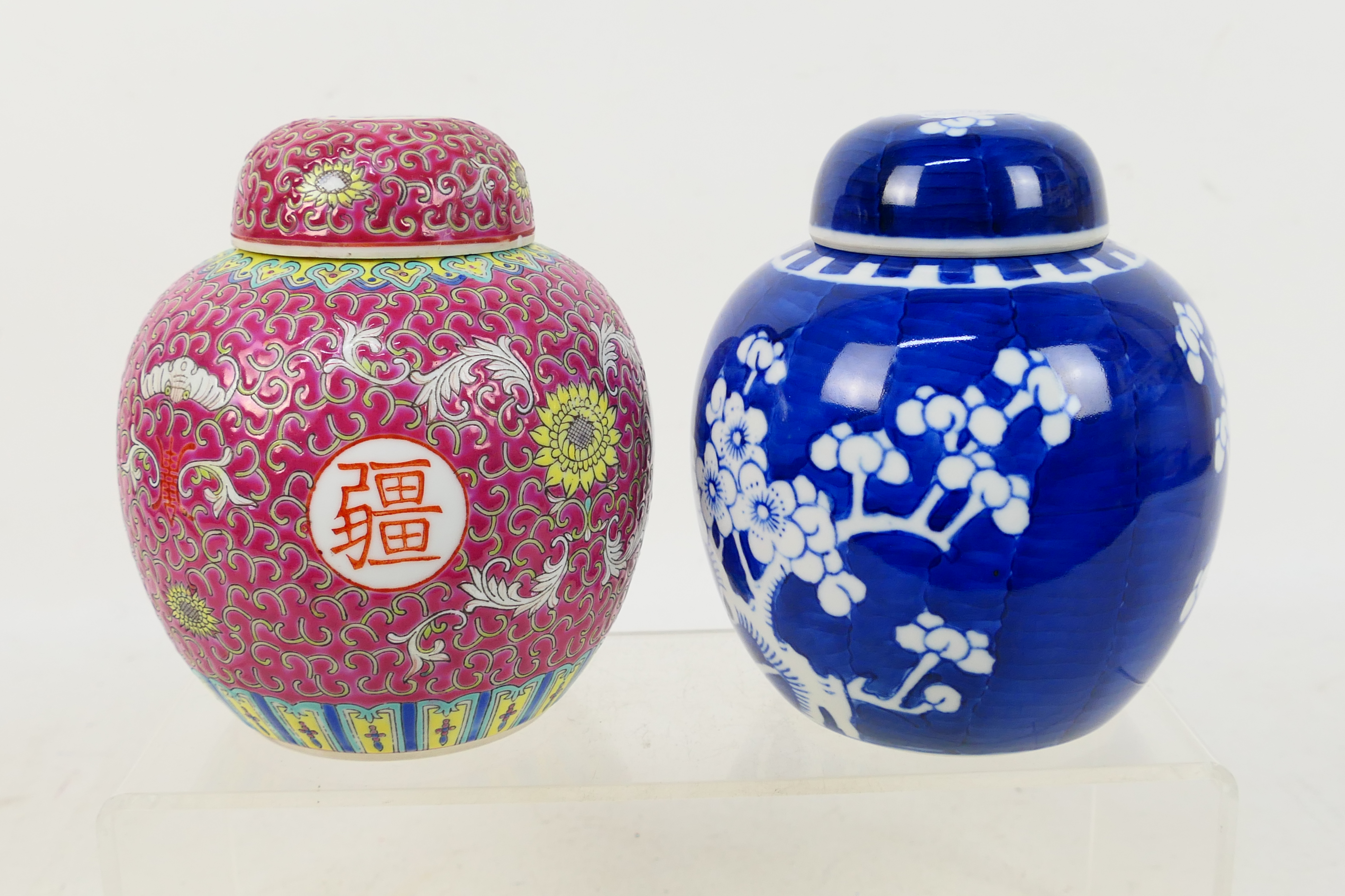 Two ginger jars and covers, one in blue and white decorated with prunus, approximately 15 cm (h).