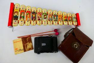 A vintage Zeiss Ikon camera contained in case and a child's glockenspiel decorated with fairytale