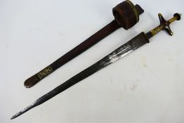 A tribal blade with tooled leather arm worn sheath, 46 cm (l) blade with brass mounted hilt.