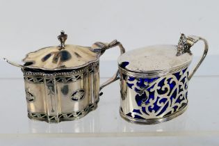 Two silver mustard pots with blue glass liners,