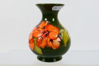 Moorcroft Pottery - A vintage vase decorated in the Hibiscus pattern reserved against a green