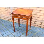 A vintage school desk with hinged top, raised on four tapering supports,