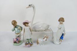 A Lladro porcelain study of a swan, 21.5 cm (h) and four Nao figures.