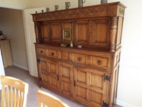 An oak court cupboard with carved decoration having an arrangement of cupboards and two drawers,