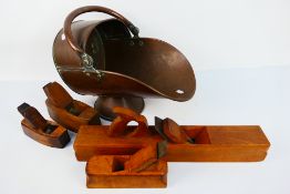 A copper coal scuttle and four vintage wooden woodworking planes.