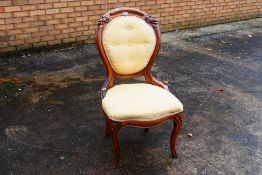 An upholstered bedroom chair with carved decoration of grapes.