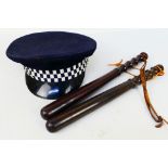 Two 20th century turned wood police truncheons, approximately 39 cm (l). and a police peaked cap.