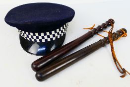 Two 20th century turned wood police truncheons, approximately 39 cm (l). and a police peaked cap.