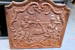 A vintage cast iron fireback depicting two men returning from hunting with their prey,