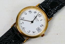 A boxed Sewills gold plated wrist watch on black leather strap, Arabic numerals to a white dial,