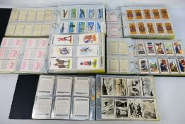 Three binders containing various sets of cigarette cards and two further binders containing larger