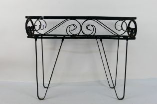A black painted wrought iron planter stand, approximately 48 cm x 62 cm x 17 cm.