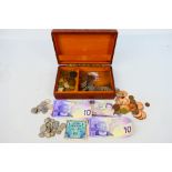 A vintage cigar box with lid depicting an angel and blacksmiths containing a quantity of coins and