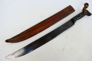 An antique machete with carved wooden grip and 45 cm (l) blade, contained in leather sheath,