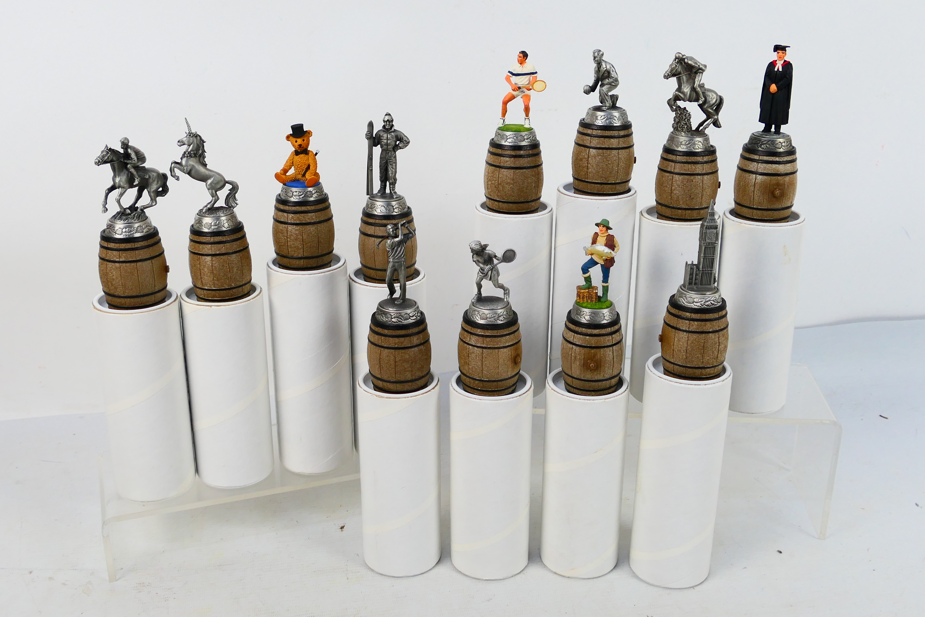 Twelve pewter, novelty bottle stoppers by Sterling Classics, contained in original packaging.