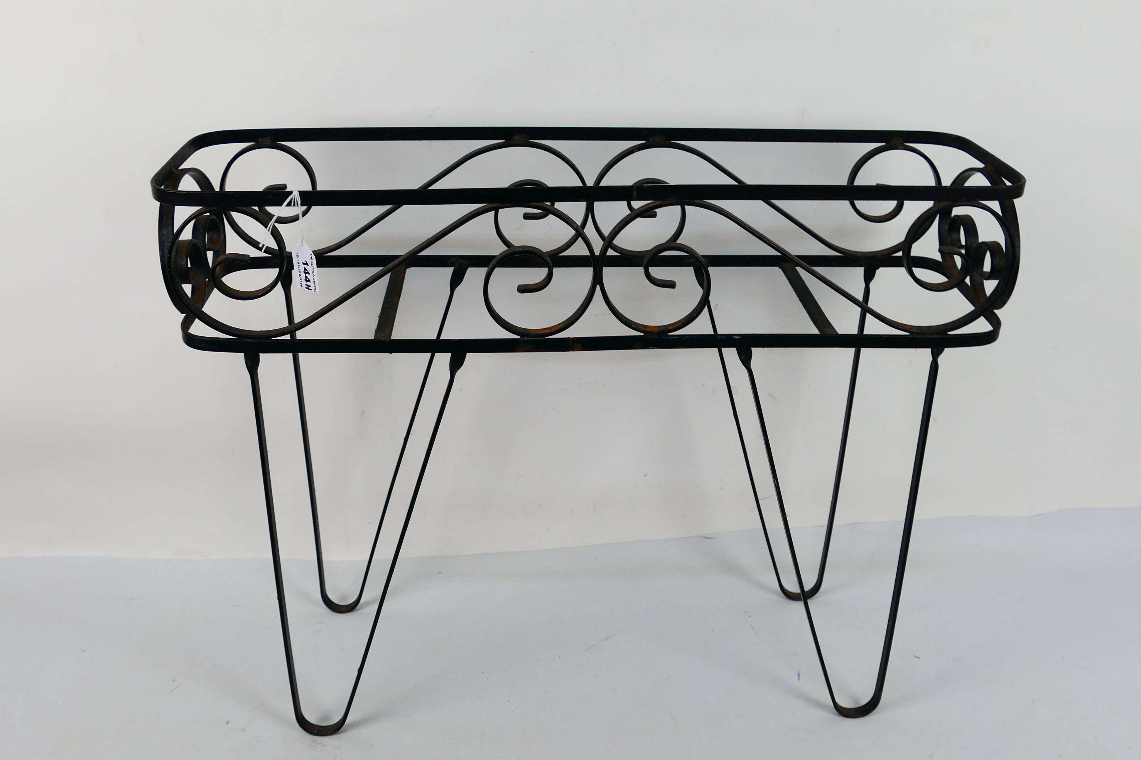 A black painted wrought iron planter stand, approximately 48 cm x 62 cm x 17 cm.