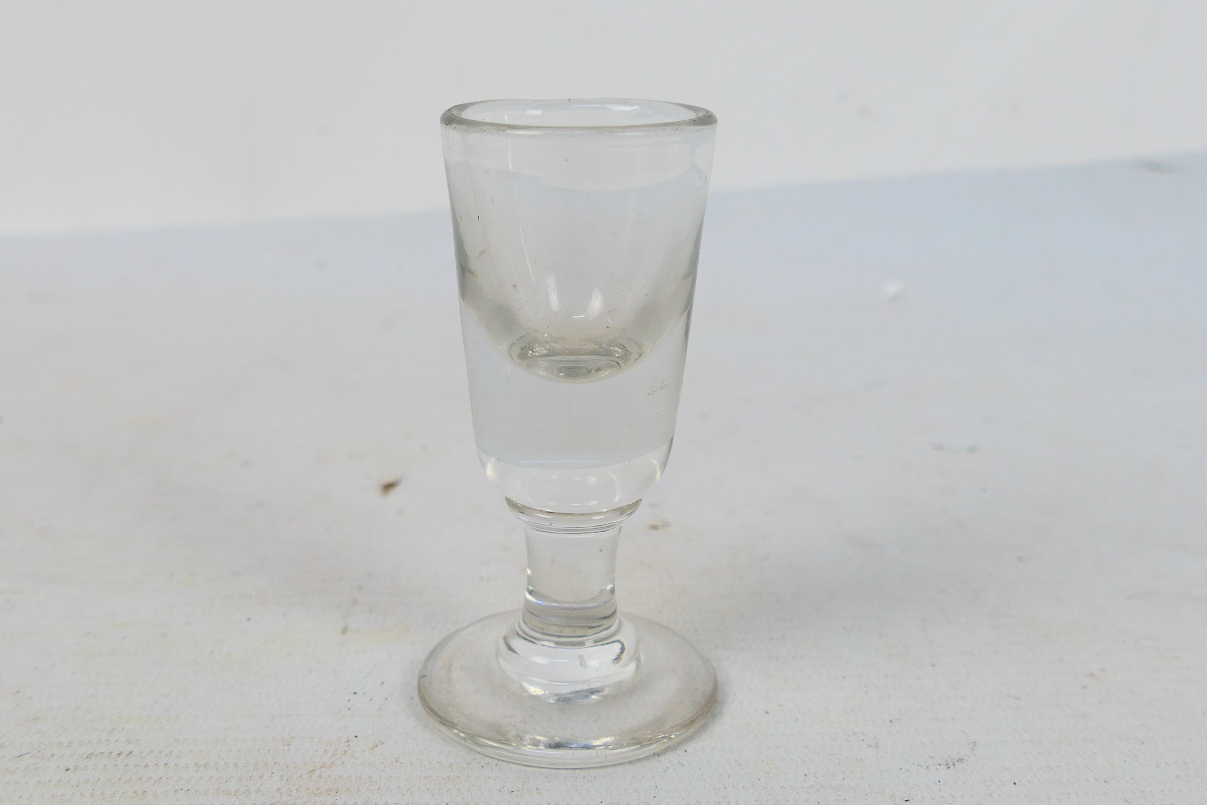 A Toastmasters firing or dram glass, round funnel bowl on cylindrical stem, approximately 9 cm (h).