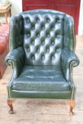 Green buttoned and studded leather wing armchair.