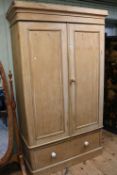 Stripped pine wardrobe having two panelled doors above a long drawer, 206cm by 120cm by 57cm.