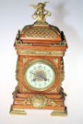 An early 20th Century oak and brass mounted mantel clock having cherub finial and enamel dial,