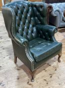 Green buttoned and studded leather wing armchair.