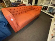 Contemporary three seater settee in orange buttoned fabric.