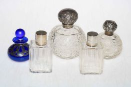 Four silver topped glass scent bottles and silver overlay bottle.